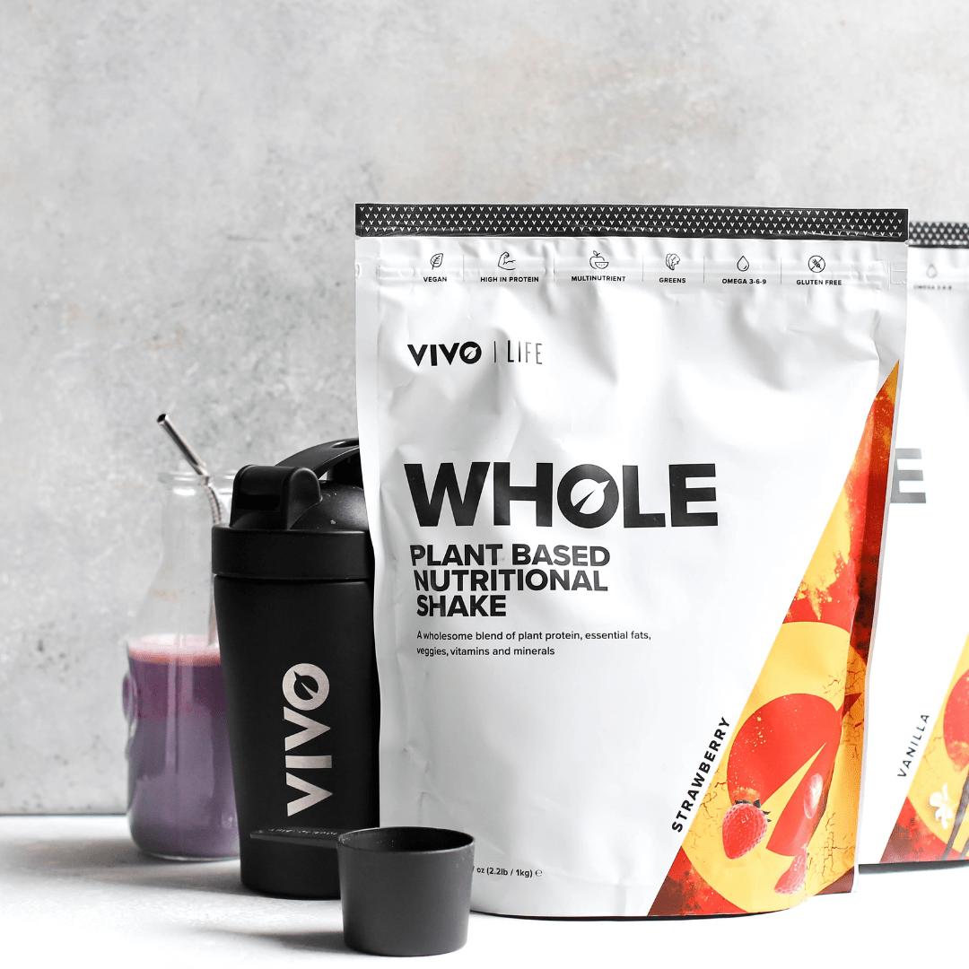 Vivo Life Whole Plant-Based Nutritional Shake supplement in a glass with mixed fruits and leafy greens on a white background.