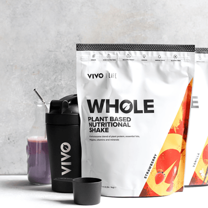 Vivo Life Whole Plant-Based Nutritional Shake supplement in a glass with mixed fruits and leafy greens on a white background.